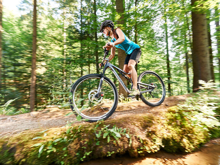 Eine Frau fährt durch einen Wald in Bodenmais im Bayerischer Wald.