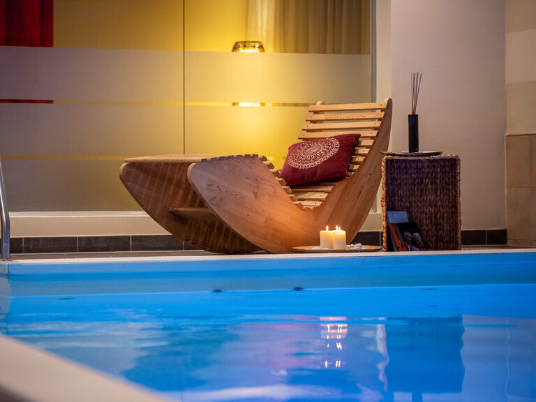 An dem großen Innenpool im Landhotel Postwirt steht Holzliege.