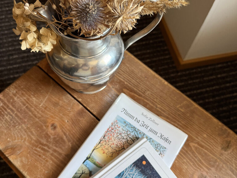 Eine Vase mit getrockneten Blumen als natürlicher Mittelpunkt auf einem Holztisch.