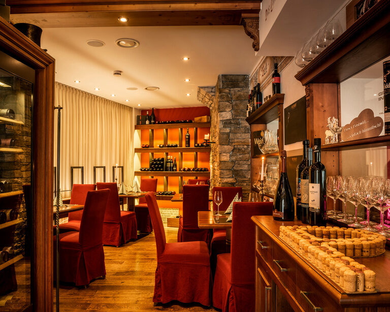 Rote Stühle in der stilvoll beleuchteten Vinothek im Landhotel Postwirt.